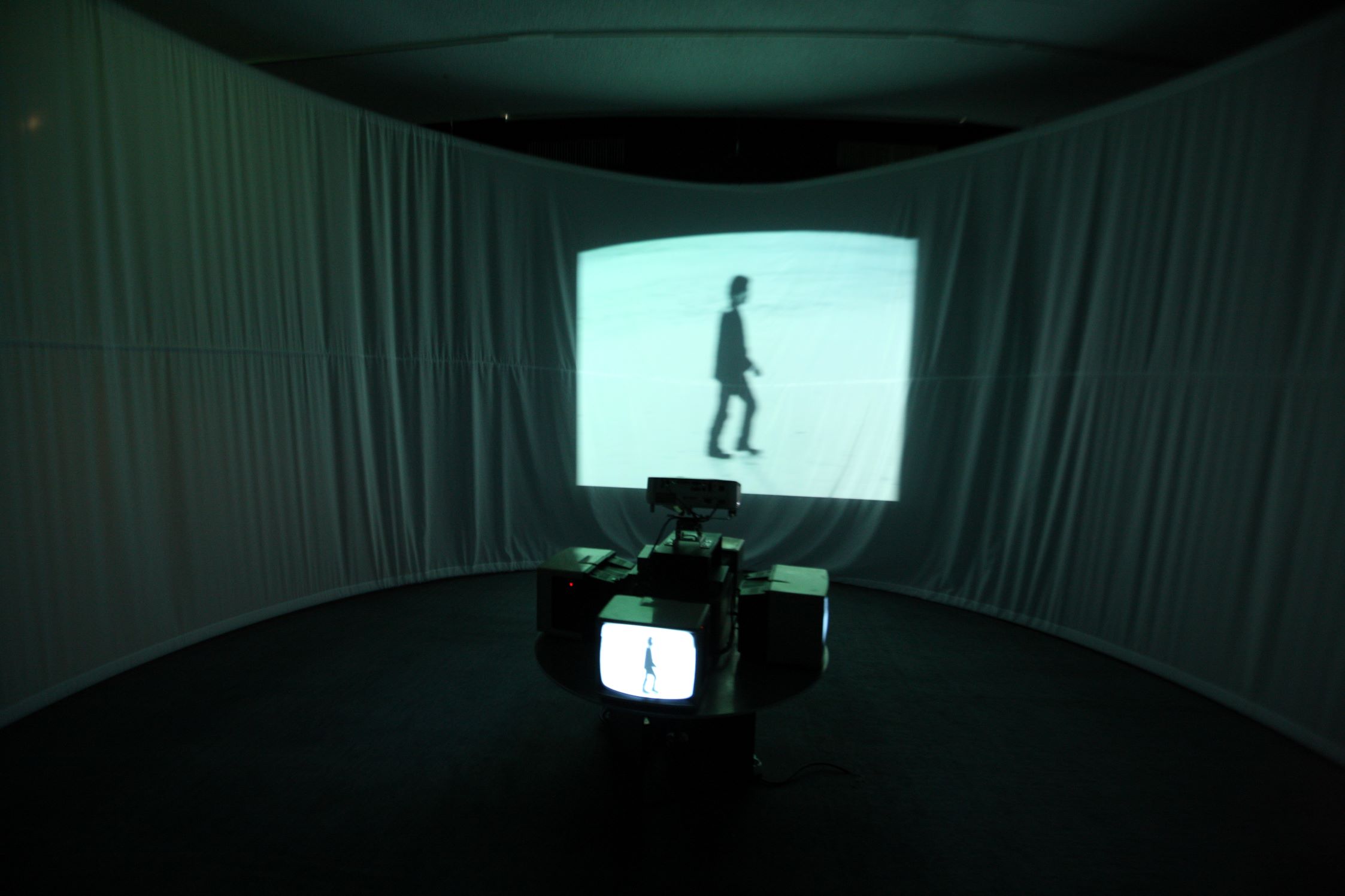 Yook Taejin, Walking Man,1996, 4 monitors, motor, DVD, projector pedestal, white curtain, 72×100×100 cm(monitor & pedestal), 2min. 52 sec. MMCA Collection. 